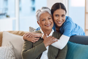 happy senior lady and caregiver hugging