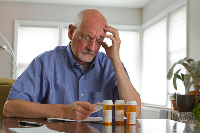 A man looks through his prescriptions to see if he takes any medications that cause falls among seniors.