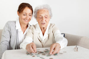 A woman spends time with her older mother putting together a puzzle. This and other activities can help create a sense of self-worth with dementia.